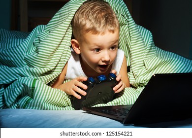 Caucasian Happy Kid Hiding Under Blanket Playing Computer Games