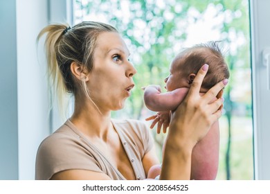 Caucasian Happy Loving Mother Holding Her First Child, Tiny Newborn Son, In The Air And Playing With Him, Showing Grice And Emotions While Standing Near The Window At Home. High Quality Photo