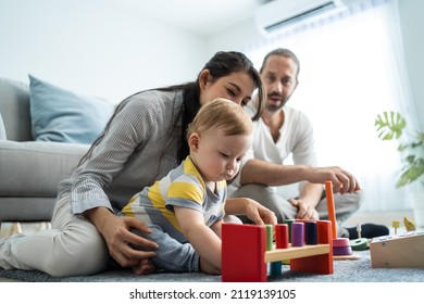 Caucasian happy loving parent play with baby toddler in living room. Attractive couple mother and father spend time with young little infant son child in house. Activity relationship at home concept.