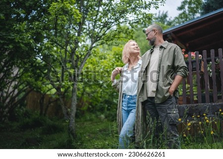 Caucasian happy relaxed middle young age couple enjoying summer in country house standing in garden