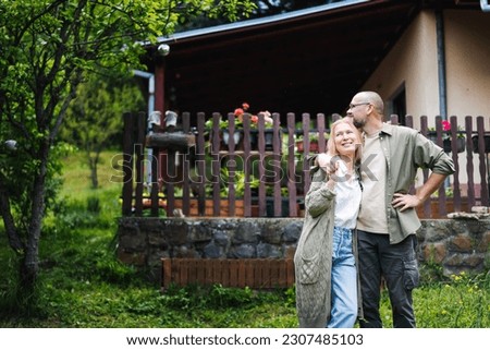 Caucasian happy relaxed middle young age couple enjoying summer in country house standing in garden