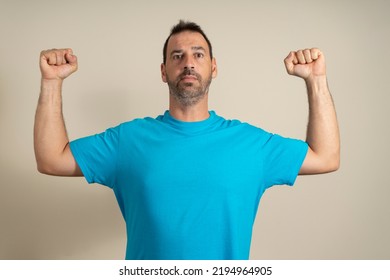 Caucasian Happy Unshaven Strong Sporty Fitness Student Male 40s In Casual Blue T-shirt Showing Biceps Muscles On Hand Isolated On Beige Background Studio Portrait