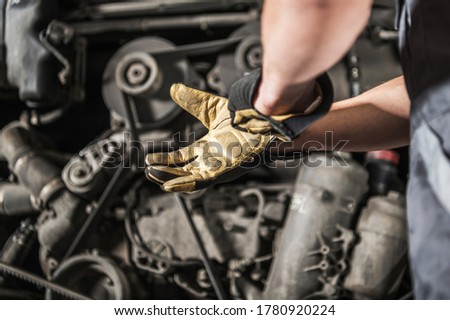 Caucasian Heavy Duty Diesel Engines Mechanic Preparing For Work Wearing Safety Gloves