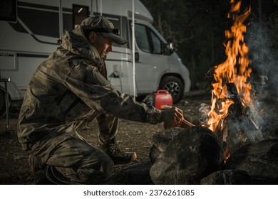 Caucasian Hunter Wearing Camouflage in Front of Campfire Next to His RV Camper Van - Powered by Shutterstock