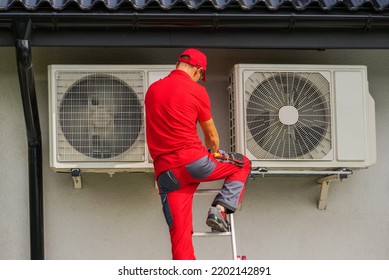 Caucasian HVAC Heating And Cooling Technician In His 40s Performing Scheduled Heat Pump And Air Condition Outdoor Units Service.