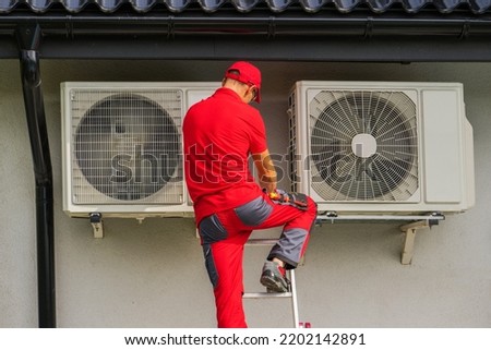 Caucasian HVAC Heating and Cooling Technician in His 40s Performing Scheduled Heat Pump and Air Condition Outdoor Units Service.