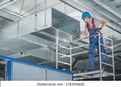 Caucasian HVAC Technician Worker in His 40s Testing Newly Installed Warehouse Ventilation System. Commercial Heating, Cooling and Air Ventilation Systems.