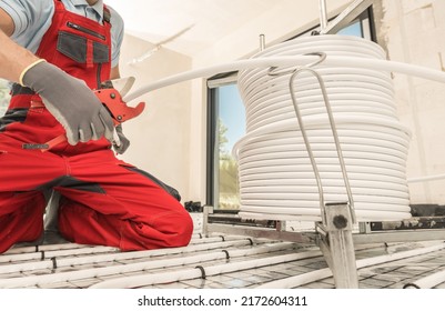 Caucasian HVAC Worker With Tube Slicer In His Hand Cutting Radiant Floor Heating Plastic Pipeline. Heating And Cooling Industry Theme.