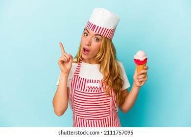 Caucasian ice cream maker woman holding an ice cream isolated on blue background having an idea, inspiration concept.
