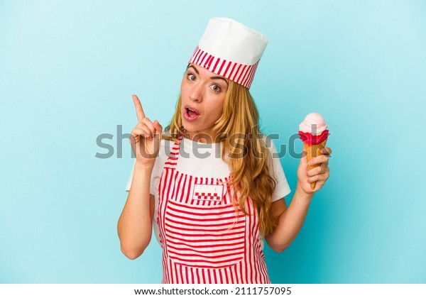 Caucasian\
ice cream maker woman holding an ice cream isolated on blue\
background having an idea, inspiration\
concept.