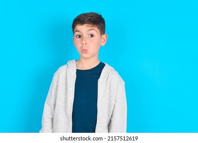 Caucasian Kid Boy Wearing Grey Hoodie Over Blue Background Expressing Disgust, Unwillingness, Disregard Having Tensive Look Frowning Face, Looking Indignant With Something.