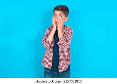 caucasian kid boy wearing plaid shirt over blue background keeps hands on cheeks has bored displeased expression. Stressed hopeless kid boy  - Shutterstock ID 2157031813