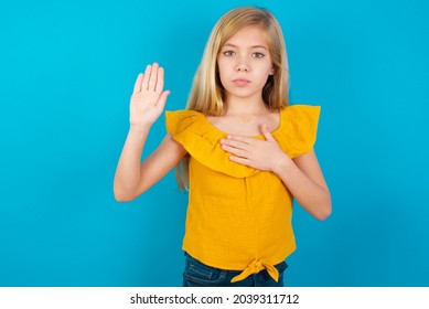 Caucasian Kid Girl Wearing Yellow T-shirt Against Blue Wall Swearing With Hand On Chest And Open Palm, Making A Loyalty Promise Oath