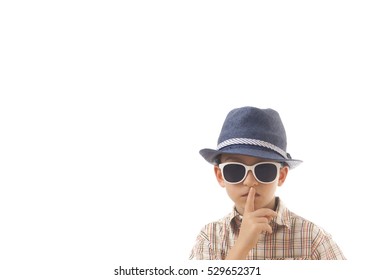 Caucasian kid with hat and sunglasses. Isolated on white background. Space for copy or other design.Keep quiet concept.