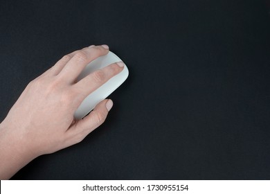 Caucasian Left-handed Woman Using Computer Mouse. Female Hand Holding Computer Mouse On Dark Black Backround.