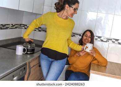 Caucasian lesbian couple in the kitchen in which one of them gives her husband a coffee to have breakfast. LGBT couple concept - Powered by Shutterstock