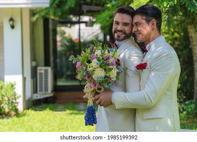 Caucasian LGBTQ Gay Couple Having Goodtime In Garden Hugging Together With Holding Flowers Bouquet In Wedding Ceremony And Marriage Celebration. Concept Of Same Sex Relation