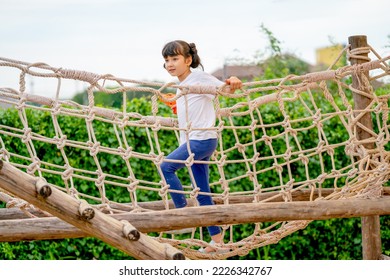 Caucasian little girl enjoy and fun to play with walking on net bridge in playground of public park. - Powered by Shutterstock