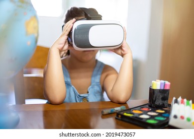 Caucasian Little Girl At Her Desk Wearing VR Glasses. Concept Of New Learning Tools.