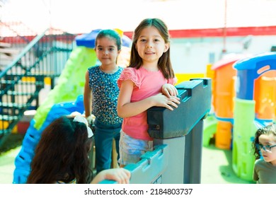 Caucasian Little Girl Smiling While Playing With Kids Classmates In The Playground During Preschool Recess