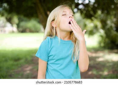 Caucasian Little Girl Wearing Blue T-shirt Standing Outdoors Being Tired And Yawning After Spending All Day At Work.