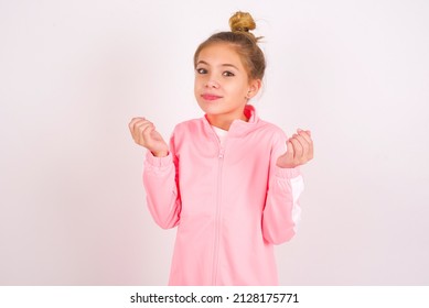 Caucasian Little Kid Girl With Bun Hairstyle Wearing Pink Tracksuit Over White Background Doing Money Gesture With Hands, Asking For Salary Payment, Millionaire Business