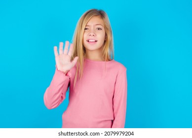 Caucasian Little Kid Girl Wearing Long Sleeve Shirt Over Blue Background Shows Middle Finger Bad Sign Asks Not To Bother. Provocation And Rude Attitude.