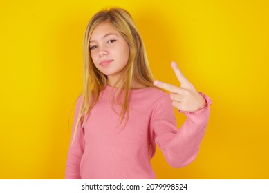 Caucasian Little Kid Girl Wearing Long Sleeve Shirt Over Yellow Background Shows Middle Finger Bad Sign Asks Not To Bother. Provocation And Rude Attitude.