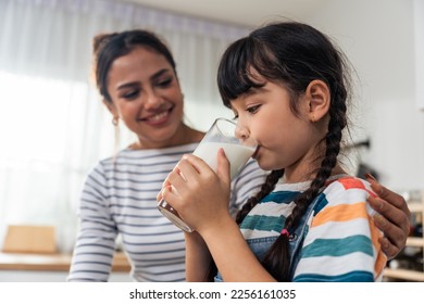 Caucasian little kid holding a cup of milk and drinking with mother. Attractive mom teach and support young girl daughter take care of her body, sipping a milk after wake up for health care in house.
 - Powered by Shutterstock