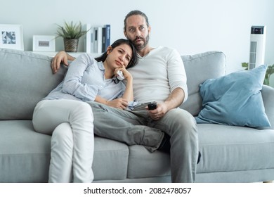 Caucasian Loving Couple Watch Movie Together In Living Room At Home. Beautiful Happy New Marriage Man And Woman Sit On Sofa Use Remote Control TV And Look To Drama And Sad Show On Television In House.