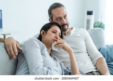 Caucasian Loving Couple Watch Movie Together In Living Room At Home. Beautiful Happy New Marriage Man And Woman Sit On Sofa Use Remote Control TV And Look To Drama And Sad Show On Television In House.