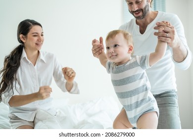 Caucasian Loving Parents Play With Baby Boy Child On Bed In Bedroom. Happy Family, Attractive Beautiful Young Couple Dad And Mom Dance With Cute Infant Toddler Son Enjoy Morning Activity After Wake Up