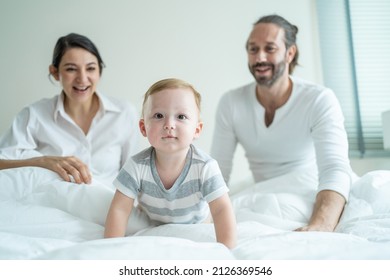 Caucasian Loving Parents Play With Baby Boy Child On Bed In Bedroom. Happy Family, Attractive Beautiful Young Couple Dad And Mom Dance With Cute Infant Toddler Son Enjoy Morning Activity After Wake Up