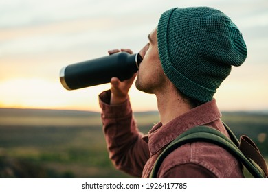 Caucasian Male Adventurer Wearing Beanie Hiking In Mountain Quenching Thirst Drinking Water 