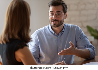 Caucasian male applicant answers on questions to HR female manager during job interview in office. Meeting process, negotiations communications between business parties, solutions and opinion concept