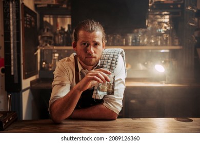 Caucasian male bartender having a drink at the bar alone after work  - Powered by Shutterstock