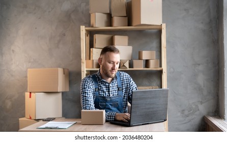 Caucasian Male Business Owner Sitting At Home Office Wearing Overalls. Using Computer, Online Marketing Packaging Box Delivery, SME E-commerce Telemarketing Concept.