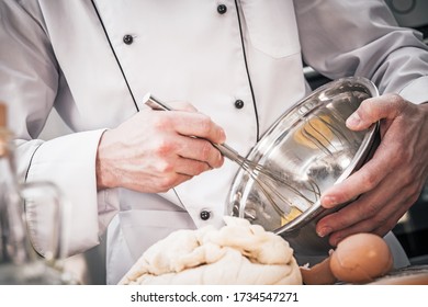 Caucasian Male Chef Mixing Batter With Wire Whisk In Stainless Steel Bowl.