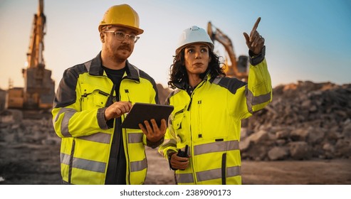 Caucasian Male Civil Engineer Talking To Hispanic Female Inspector And Using Tablet Computer On Construction Site of New Building. Real Estate Developers Discussing Business, Excavators Working. - Shutterstock ID 2389090173