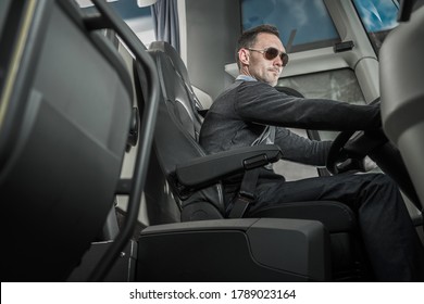 Caucasian Male Coach Bus Driver In His 40s Behind Vehicle Steering Wheel. Public Transportation Theme.