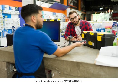 Caucasian male customer buying a tool box at the hardware store while taking with an employee at the checkout