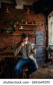 Caucasian Male Customer Sipping Hot Coffee Texting On Cellular Device In Cafe 