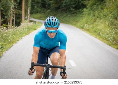 Caucasian Male Cyclist With Professional Racing Sports Gear Riding On An Open Road Cycling Route Through A Forest