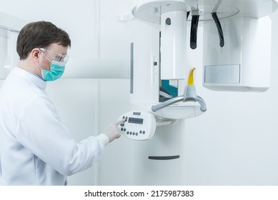 Caucasian Male Dentist Wear Mask Standing Prepare In Dental Exam Room. Handsome Young Man Dental Doctor In Uniform Preparing Equipment X-ray Machine For Patient In Dental Examination Room At Clinic.