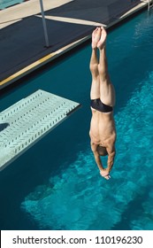Caucasian male diver diving upside down into the pool