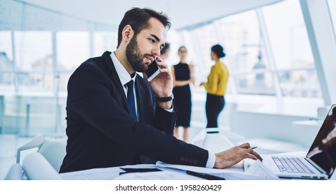 Caucasian male entrepreneur planning work process analyzing business exchange browsed on laptop computer, confident professional discussing web information during smartphone communication with partner - Shutterstock ID 1958260429
