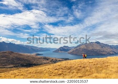 Caucasian male and female New Zealand adventure hikers on their travel trekking vacation viewing scenic Lake Wakatipu The Remarkables Otago