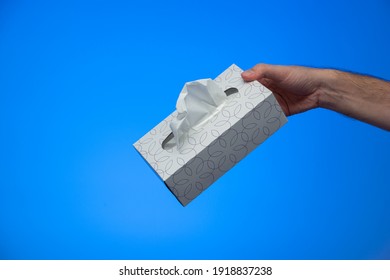 Caucasian Male Hand Holding A Box Of Paper Sanitary Tissues Making An Offering Gesture Isolated On Blue Background Studio Shot.