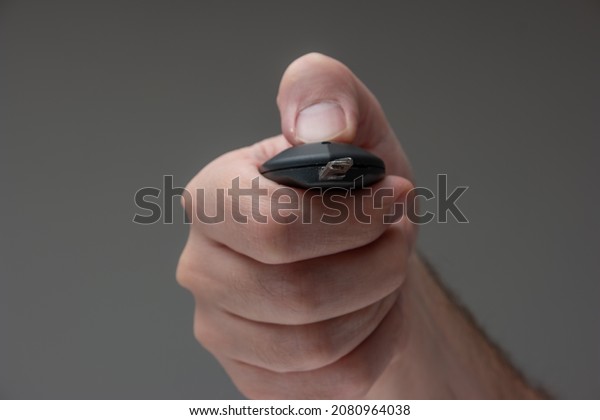 Caucasian male hand holding a car key fob. Close up\
studio macro sho.