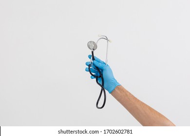 Caucasian male hand, wearing medical gloves, holding a stethoscope, white background